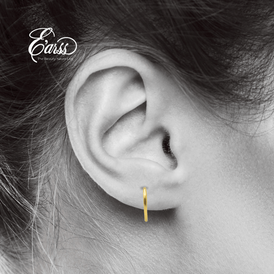 Close-up of an ear wearing a gold hoop earring with 'Earrs' branding.
