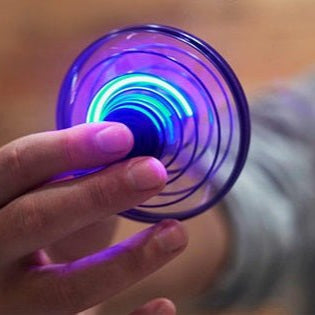 Hand holding a glowing fidget spinner with a blurred background
