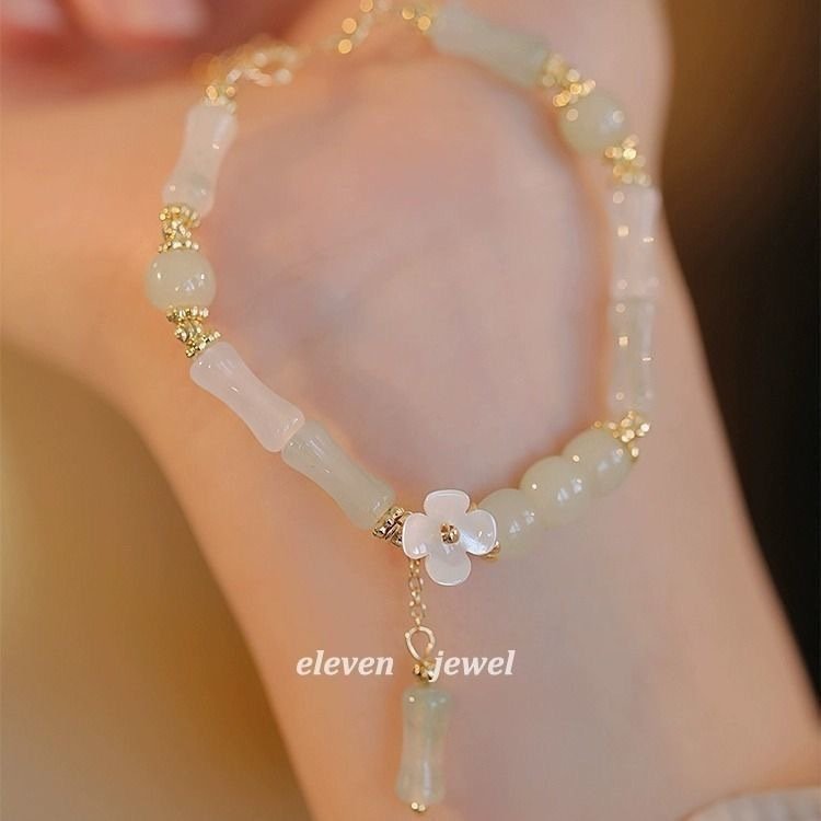 Necklace with floral pendant on a blurred background, featuring the brand 'eleven jewel'.