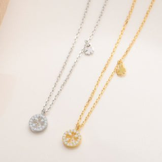 Two necklaces, one gold and one silver, on a light background