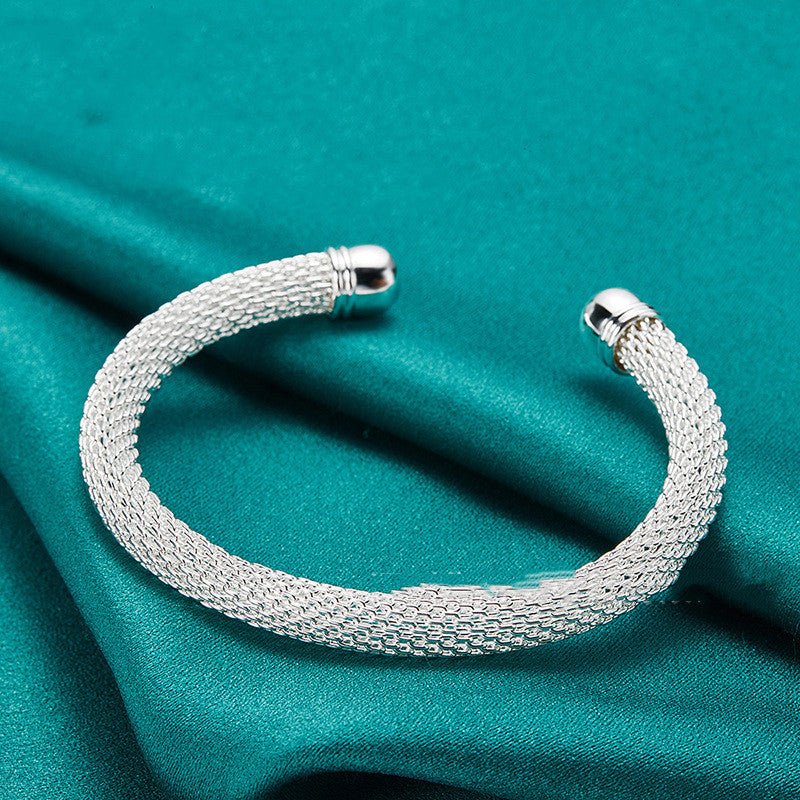 Silver bracelet on a teal fabric background