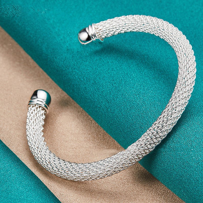 Silver mesh bracelet on a turquoise and beige fabric background
