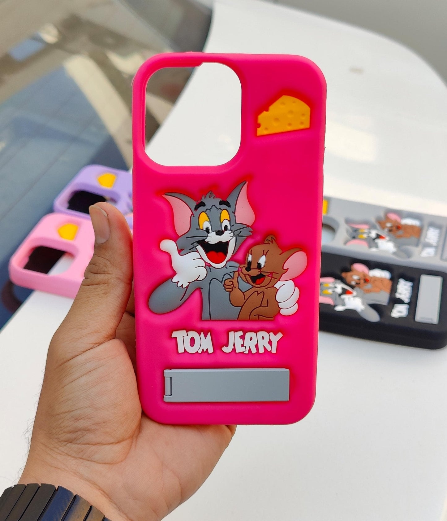 Pink phone case with Tom and Jerry design held by a hand on a blurred background