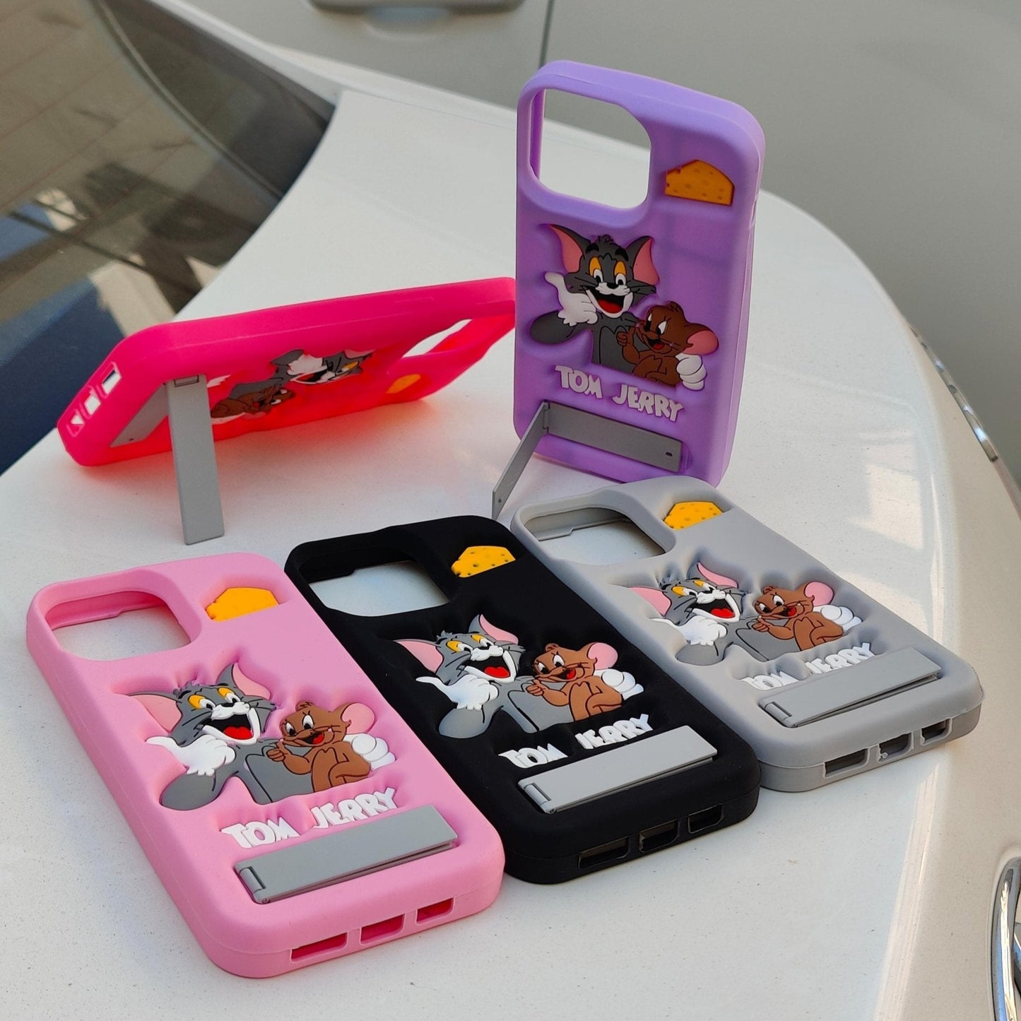 Four phone cases with Tom and Jerry design on a white surface