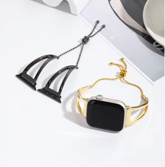 Gold and black watch bands on a white surface with a cup and saucer in the background.