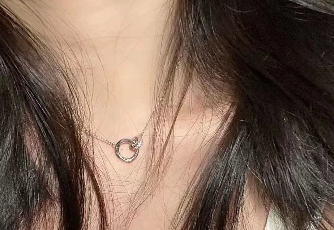 Necklace with a small circular pendant worn by a person with dark hair.