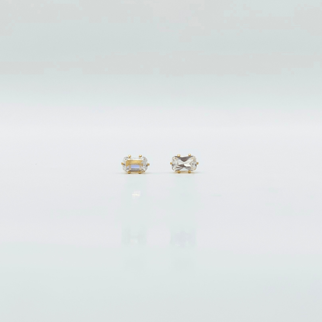 Two gold stud earrings on a light gray background