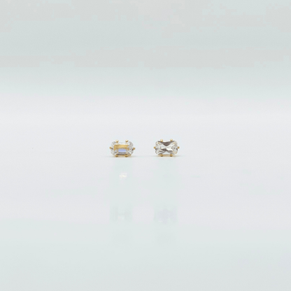 Two gold stud earrings on a light gray background