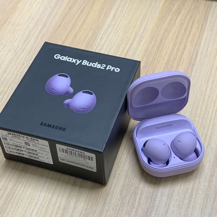 Purple Samsung Galaxy Buds2 Pro earbuds with open charging case on a wooden surface.