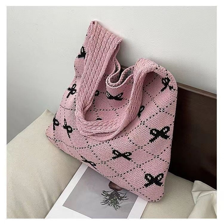 Pink knitted bag with black patterns on a light surface