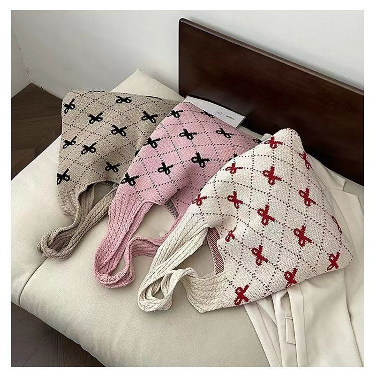 Three knitted bags with patterned designs on a bed.