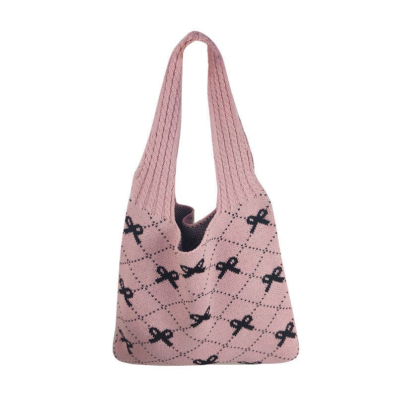 Pink knitted bag with black bow pattern on a white background
