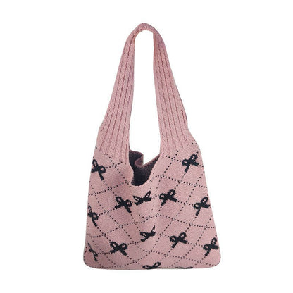 Pink knitted bag with black bow pattern on a white background