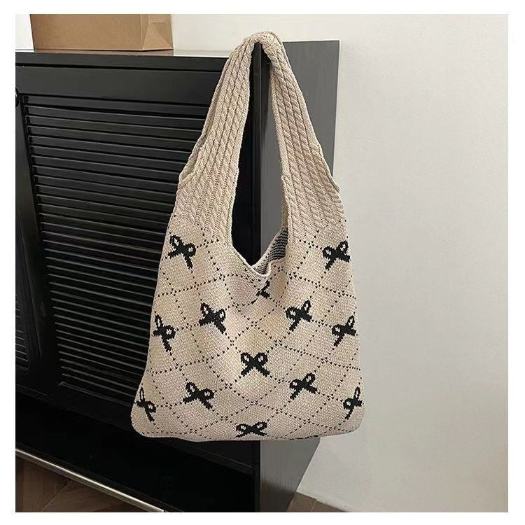 Beige woven bag with black bow pattern on a black surface