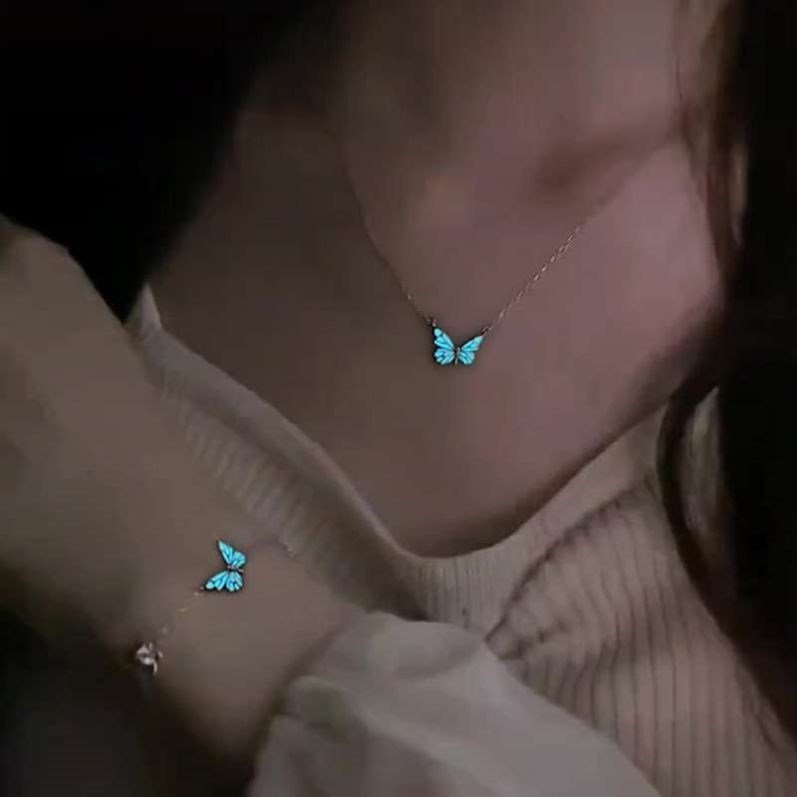 Person wearing a necklace and bracelet with glowing blue butterfly designs.