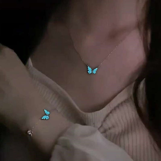 Person wearing a necklace and bracelet with glowing blue butterfly designs.