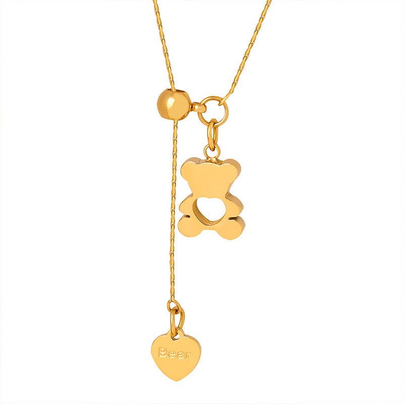 Gold necklace with a bear pendant and heart-shaped tag on a white background