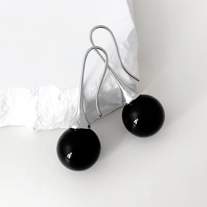 Black spherical earrings on a white background