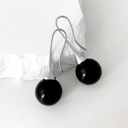Black spherical earrings on a white background