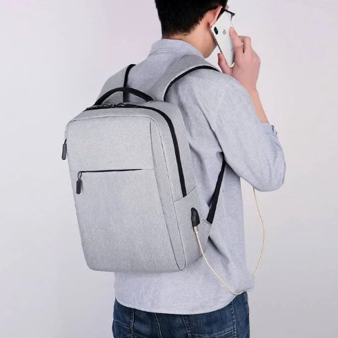 Person wearing a gray backpack and using a smartphone on a plain background