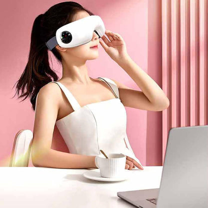 Woman using an eye massager at a desk with a pink curtain background
