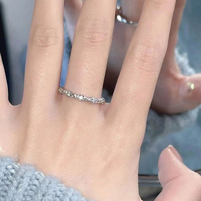 Close-up of a hand wearing a silver ring with small stones on a blurred background