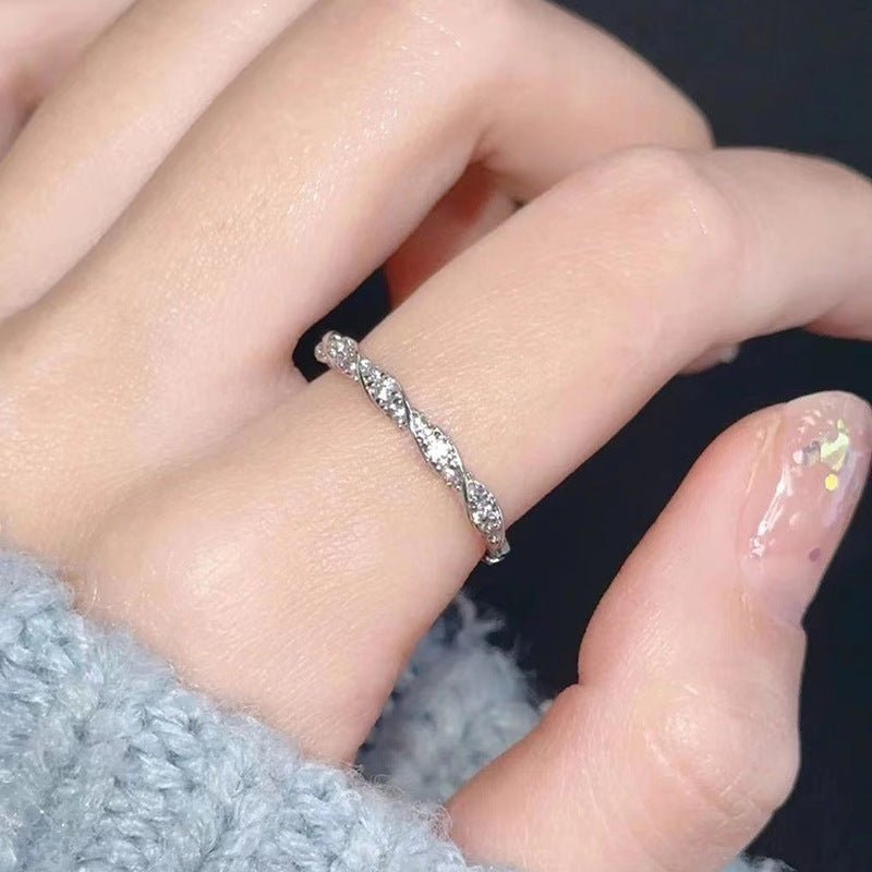 Close-up of a hand wearing a silver ring with small stones.