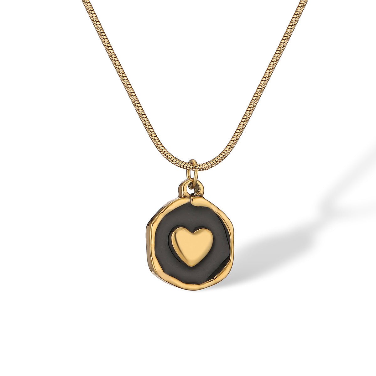 Gold necklace with a black pendant featuring a heart design on a white background