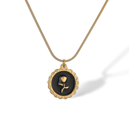 Gold necklace with a black pendant featuring a rose design on a white background
