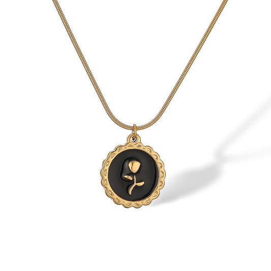 Gold necklace with a black pendant featuring a rose design on a white background
