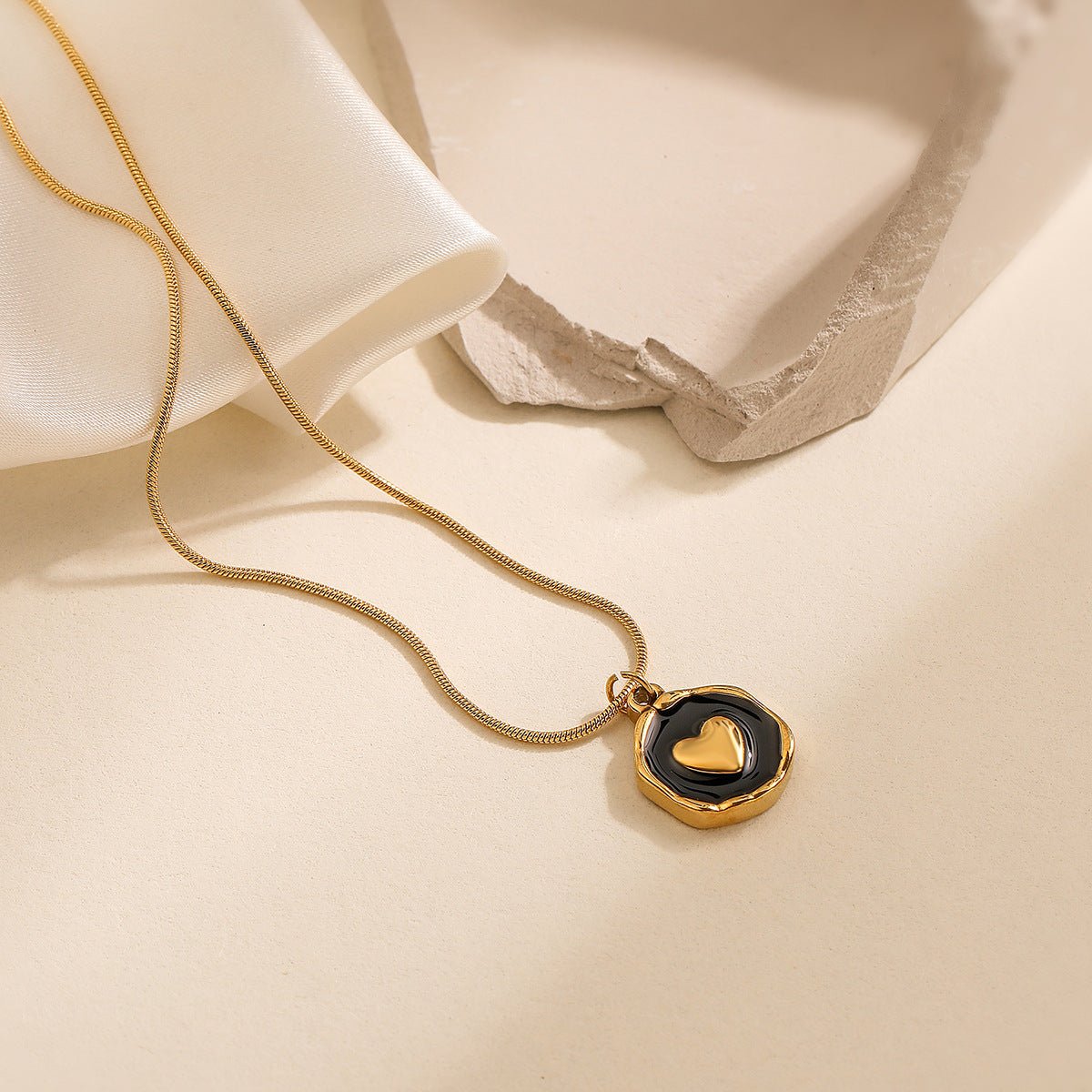 Gold necklace with a heart pendant on a beige fabric background