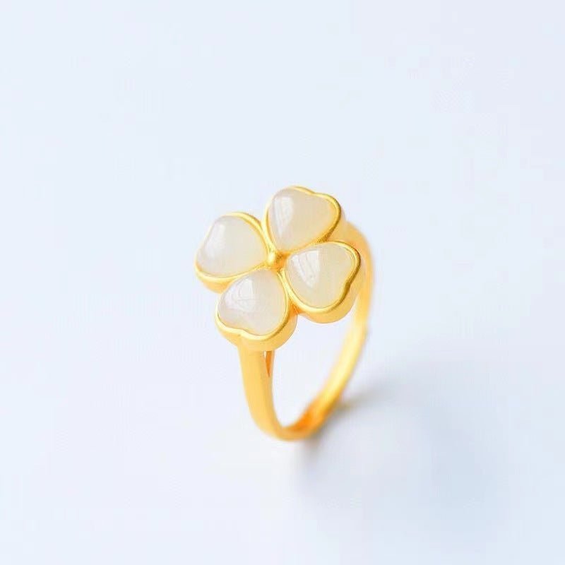 Gold ring with three heart-shaped stones on a light gray background
