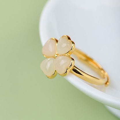 Gold ring with three heart-shaped stones on a white surface with a green background