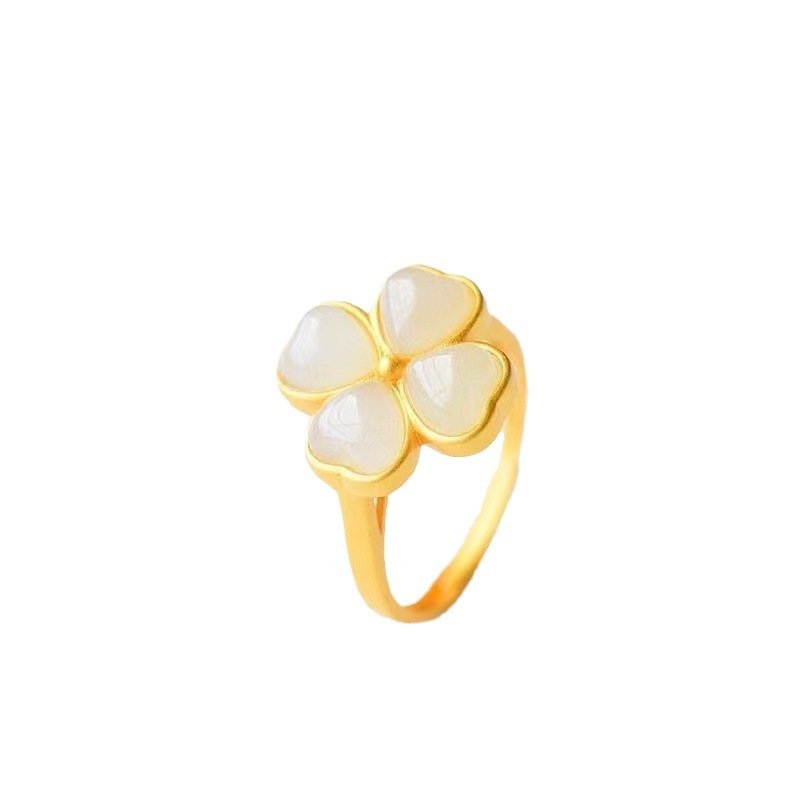 Gold ring with three heart-shaped white stones on a white background