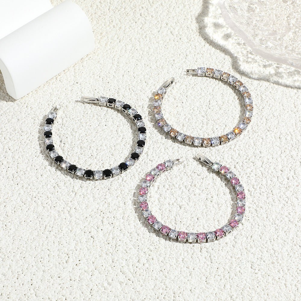 Three pairs of hoop earrings with different color schemes on a textured white surface.