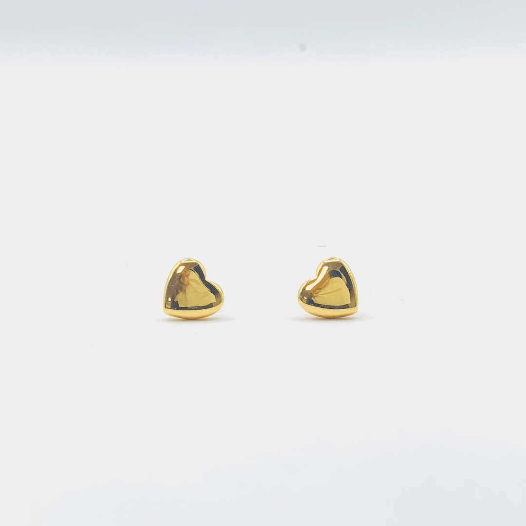 Gold heart-shaped earrings on a light gray background