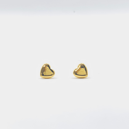 Gold heart-shaped earrings on a light gray background