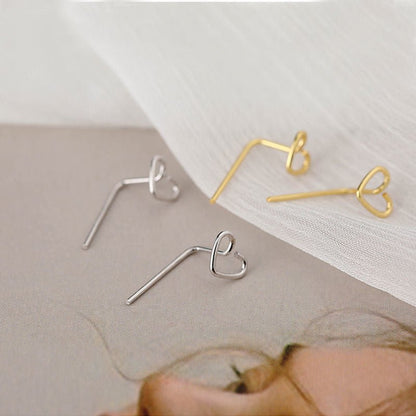 Gold and silver heart-shaped earrings on a neutral background