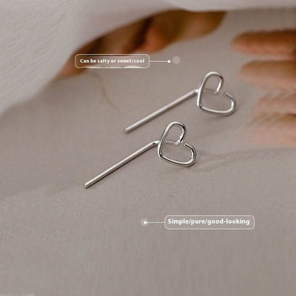 Heart-shaped silver earrings on a neutral background