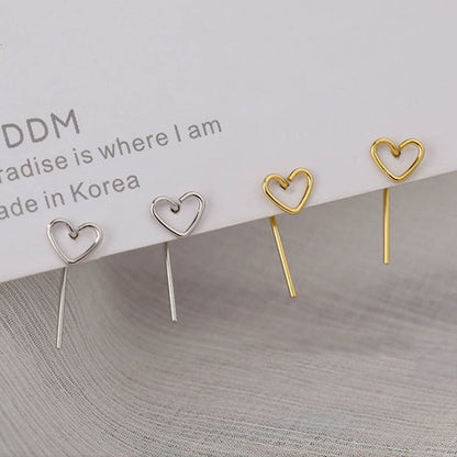 Heart-shaped earrings in gold and silver on a textured surface with text in the background.