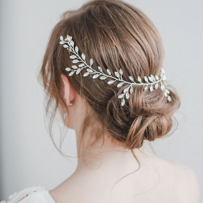 Woman with a decorative hairpiece wearing a white dress against a light background