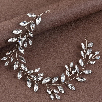 Silver leaf-shaped jewelry piece on a brown fabric background