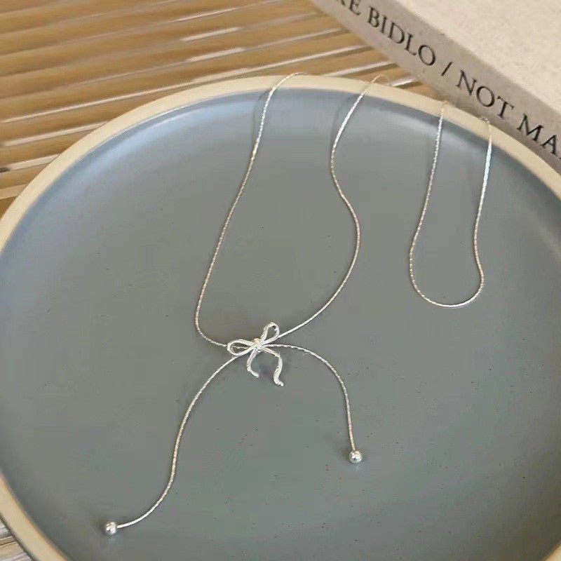 Silver necklace with a bow pendant on a gray plate