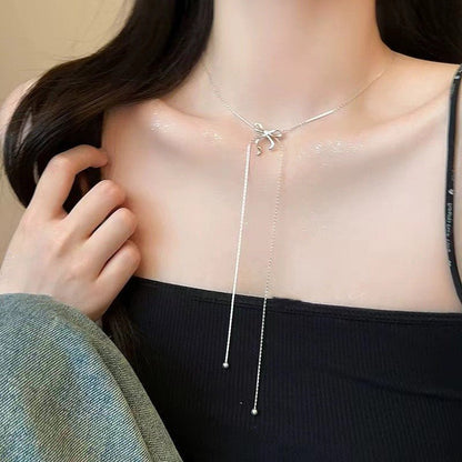 Silver necklace with a bow pendant worn by a person