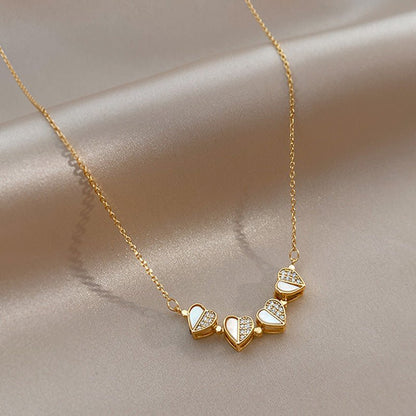 Gold necklace with heart-shaped pendants on a beige fabric background