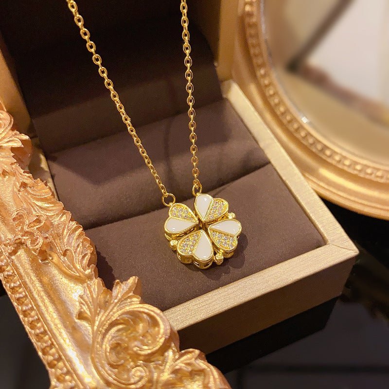Gold necklace with a clover-shaped pendant on a brown cushion in an ornate gold box.
