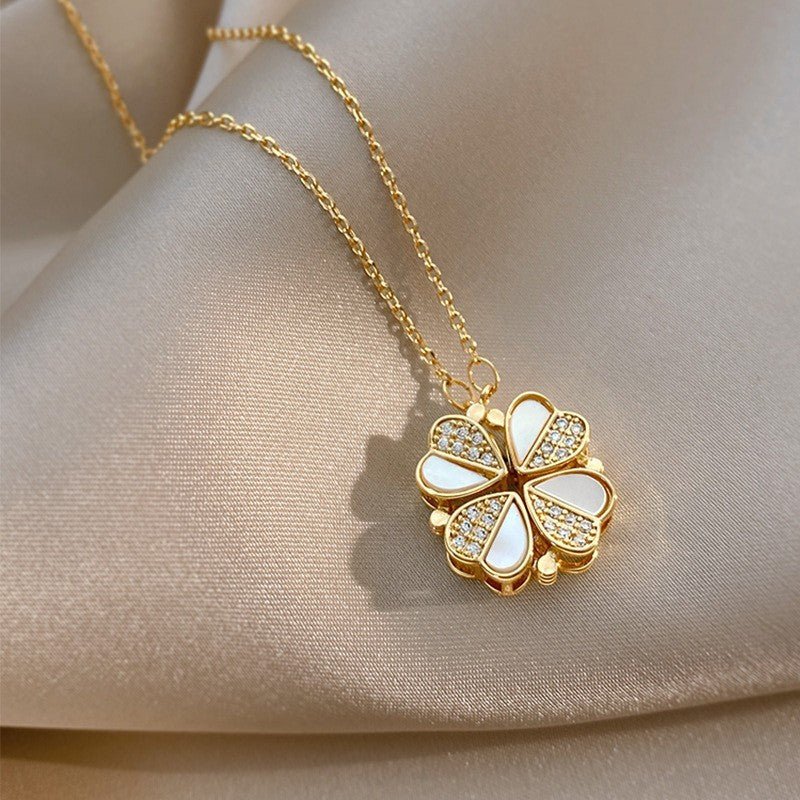 Gold necklace with a four-leaf clover pendant on a beige fabric background