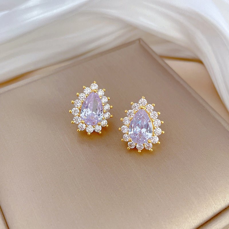 Pair of gold earrings with pink gemstones on a beige surface