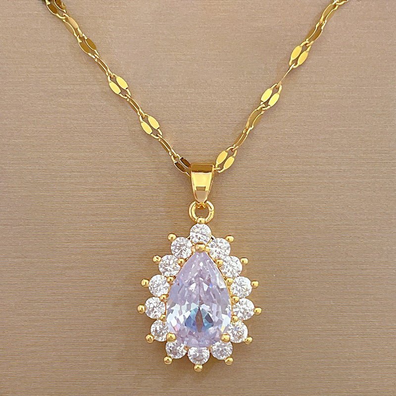 Gold necklace with a pendant featuring a purple teardrop-shaped gemstone on a beige background
