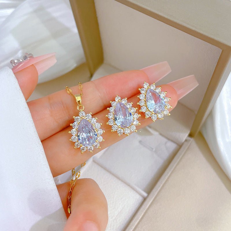 Gold jewelry set with pear-shaped gemstones on a hand